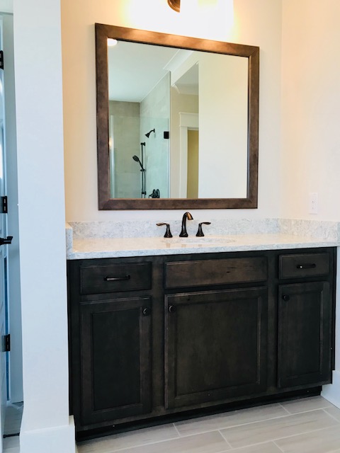 Dark-stained bathroom vanity with a wood-framed mirror installed in Daniel Island, SC