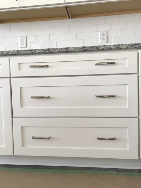 Close-up of white Shaker drawer bank with brushed nickel pulls in a North Charleston kitchen