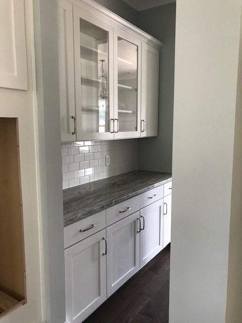 White kitchen cabinets with glass-front uppers and subway tile backsplash in Mount Pleasant, SC