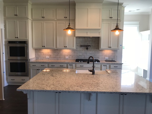 Finished white Shaker kitchen with granite island, pendant lights, and double wall ovens in Summerville, SC
